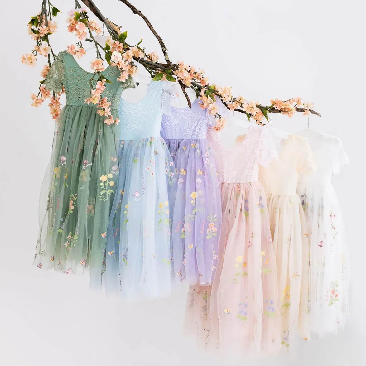 Enchanted Willow Dresses in various colours hanging from a branch